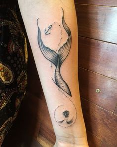 a woman's arm with a black and white tattoo design on the left forearm