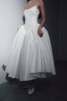 a woman in a white dress is posing for the camera