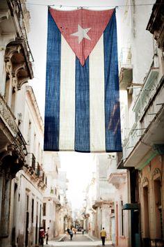 a cuba flag hanging from the side of an old building on a street in havana, cuba