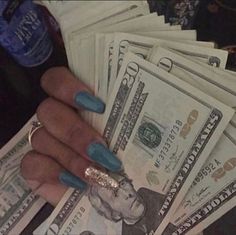 a woman's hand with blue fingernails holding money