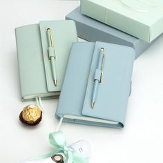 two notebooks and pen sitting next to each other on top of a white table