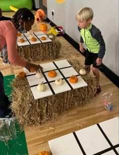 two children are playing with pumpkins on hay bales