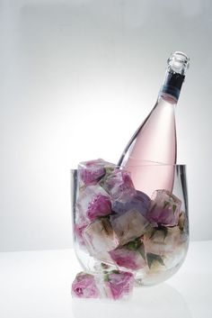 a glass filled with pink flowers next to a bottle