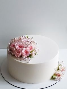 a white cake topped with pink flowers on top of a white tablecloth covered plate