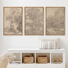 three paintings hang on the wall above a white bench with two baskets and shoes underneath it