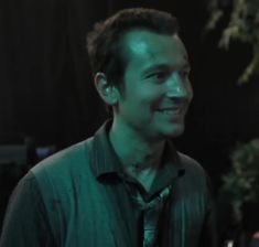 a man smiling while wearing a green shirt and tie