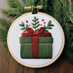 a cross stitch ornament with a green present box and red ribbon on it