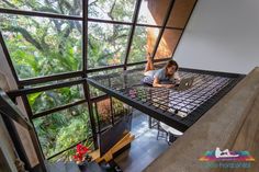 a woman sitting on top of a metal platform in front of a window with lots of plants