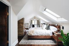 an attic bedroom with a bed, nightstands and plants in the corner on the floor