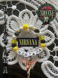 a white doily with the name nirvana on it and a yellow angel figurine