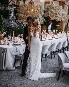 a bride and groom standing in front of a table with candles