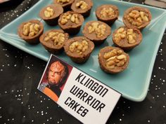 a blue plate topped with mini cupcakes covered in walnuts