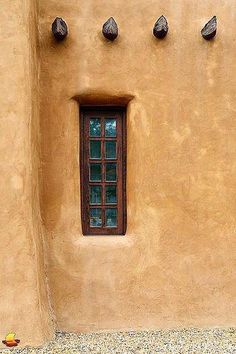 an adobe building with three windows and four birds on the wall