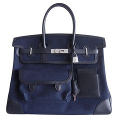 This rare "Cargo" Birkin is of Cloth / Swift Leather with palladium hardware and features five outer pockets, a removable cup holder, a front flap, two straps with center toggle closure, a clochette with lock and two keys, and double rolled handles. Details: Brand: Hermès Model: Birkin Cargo Size: 35 Material: Cloth / Swift Leather Color: Black Hardware: Palladium (PHW) Dimensions: Width: 13.8 in, Height: 10.6 in, Depth: 7.5 in Purchase Date: 2022 Condition: Mint Condition (Like New Without Any Signs of Wear) Scope of Delivery: Original Box Please contact us directly if you have any additional questions. About us: Cashingdiamonds is not an authorized dealer or licensor of any of the products we sell. We do not claim any rights to the trademarks, copyrights, patents, or any other intellectu Blue Hermes Bag, Hermes Cargo, Hermes Birkin Blue, Cargo Birkin, Blue Birkin, Modernist Jewelry, Togo Leather, Kelly Bag, Vintage Hermes