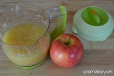 an apple sitting next to a blender filled with liquid on top of a wooden table