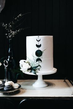 a white cake sitting on top of a table next to a vase filled with flowers