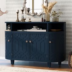 a blue sideboard with an ornate design on the doors and drawers, in front of a mirror