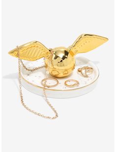 a golden bird figurine sitting on top of a white plate with gold chains