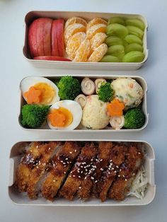 three trays filled with different types of food on top of a white countertop