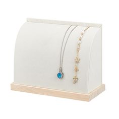 a white display case with two necklaces and a blue bead on the front