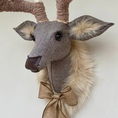 a stuffed deer head hanging on the wall with a bow around it's neck