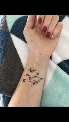 a woman's arm with a small dinosaur tattoo on it