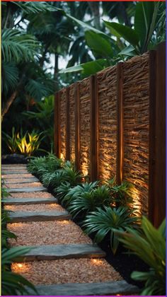 a stone path is lit up by lights in the middle of some plants and trees