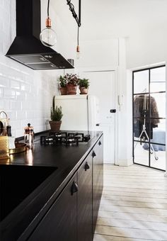 a black and white kitchen with potted plants on the stove