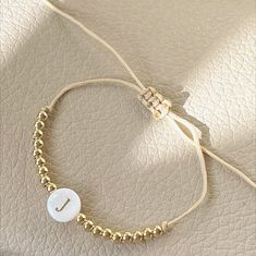 Whether you prefer an initial, a name or a phrase, this bracelet is simply a beautiful piece. Handmade with love and 2mm gold plated beads & mother of pearls initials. It is adjustable. It goes to any wrist size. Click on "Customize it" and then on the "Note" box add the letter, name or word you would like. Elegant Gold Friendship Bracelets With Letter Beads, Elegant Adjustable Friendship Bracelets With Letter Beads, Adjustable Pearl Bracelet With Gold Beads As A Gift, Dainty Gold Friendship Bracelet With Letter Beads, Dainty Adjustable Beaded Bracelets, Adjustable Pearl Bracelet With Gold Beads For Gift, Adjustable Gold Beaded Pearl Bracelet Gift, Gold Friendship Bracelets With Letter Beads, Adjustable Personalized Pearl Bracelet For Friendship