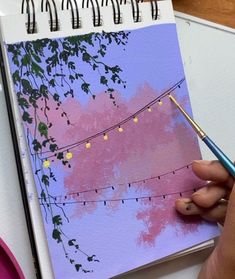 a person is holding a pen and writing on a notepad with an image of a pink tree