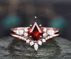 a close up view of a ring with a red stone in the middle and two white diamonds on top