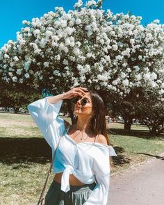 a woman taking a selfie in front of a tree with white flowers on it