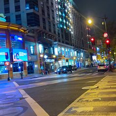 an empty city street at night with traffic lights and tall buildings in the back ground