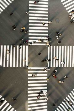 an overhead view of people walking across a crosswalk in the city with zebra crossing