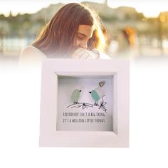 a woman holding up a white frame with two birds on it that says, there's always time for a big thing to happen