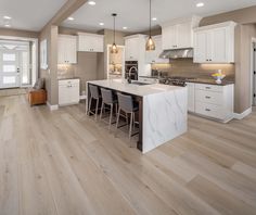 a large kitchen with white cabinets and wooden floors