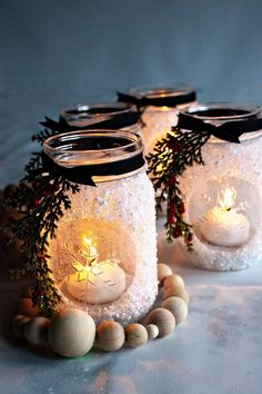 three mason jars filled with snow and lit candles