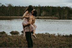 a man holding a woman in front of a lake