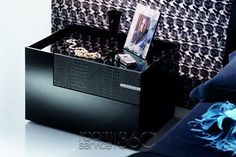 a black box with pictures and jewelry in it sitting on a white table next to a couch