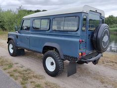 a blue jeep parked next to a body of water