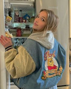 a woman is standing in front of an open refrigerator