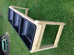 three black trays sitting on top of a wooden table in the grass next to a bench