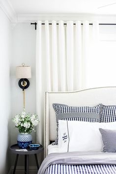 a bed with blue and white sheets in a bedroom next to a lamp on a table