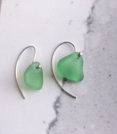 "Bring a piece work of the sea with you. Authentic sea glass that I have found along the shore, after being tumbled by the surf upon the sand and rocks, making it smooth and frosty naturally! I have hand-drilled genuine pieces of sea glass and set them onto sterling silver or gold filled hoops. All natural sea glass varies in shape. These sea glass hoops earrings are fun and a little flirty. Genuine sea glass from California available in - Emerald Green - White - Brown/Amber - seafoam. Please le Green Sea Glass Earrings For Gift, Minimalist Beach Jewelry With Ear Wire, Green Ocean-inspired Nickel-free Jewelry, Handmade Sea Glass Green Earrings, Green Sea Glass Earrings With Ear Wire, Minimalist Nickel Free Sea Glass Jewelry, Minimalist Nickel-free Sea Glass Jewelry, Green Recycled Glass Earrings For Beach, Minimalist Green Jewelry With Recycled Glass