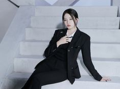 a woman sitting on some steps wearing a suit and tie