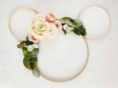 a mickey mouse ears headband with flowers and leaves on it, sitting on top of a white surface