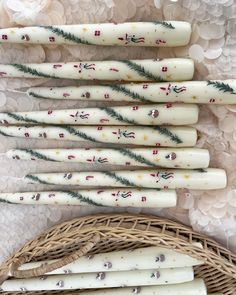 six white candles with green and red designs on them sitting in a wicker basket