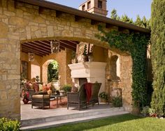 an outdoor living area with stone walls and furniture on the patio, surrounded by greenery