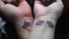 two people with matching tattoos on their wrists, both showing the same cross tattoo