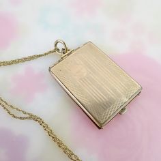 Four photos can be held within this antique gold filled locket pendant fob. The large rectangle pendant measures 1 9/16 (not including bail) inches by 1 1/8 inches and hangs from a 14k gold filled chain. The inside has a hinged frame with oval opening, in which two photos could be placed back to back. The rectangle panels can also hold large images. The front is linear engraved with a blank circular area meant for a monogram. There is a slight dimple and surface scratches to the front. The back is plain, also with a ding and visible scratches. The locket closes, but slightly askew, leaving a gap. The pendant hangs from a hinged triangle bail and large jump ring. The vintage twisted rope chain stretches 17 1/2 inches long and closes with a spring ring/end hallmarked, "1/20 14k GF, 14/20 GF" Locket Gold, Hinged Frame, Rectangle Pendant, Photo Locket, Locket Necklace, Rope Chain, Spring Rings, Antique Gold, Locket